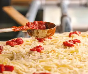 Red sauce dollops going on the pizza.