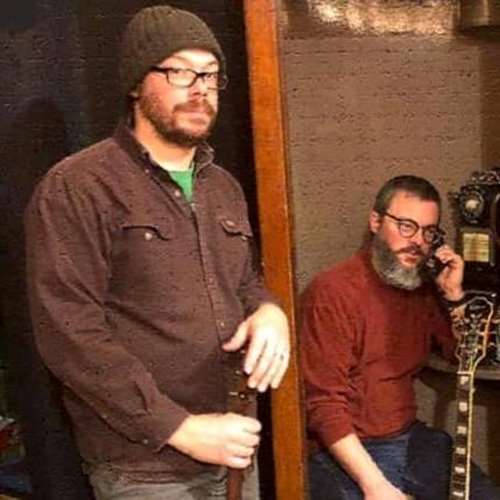 2 men sitting with their guitars