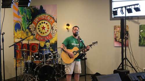Jerborn playing on stage with a guitar. Drum set behind him