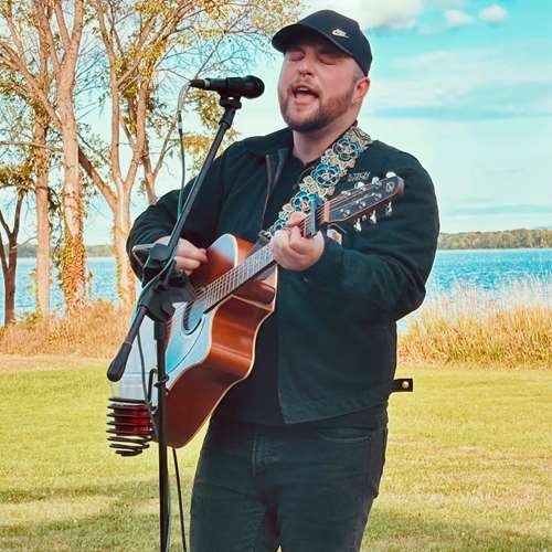 Jesse Agan playing music in front of a body of water