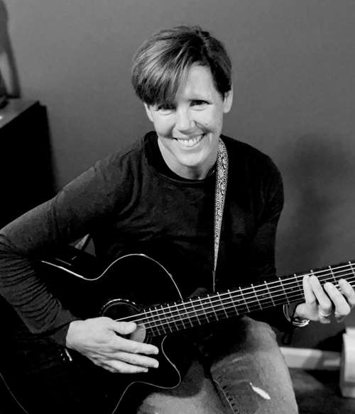 Mary Mercik smiling and playing the guitar