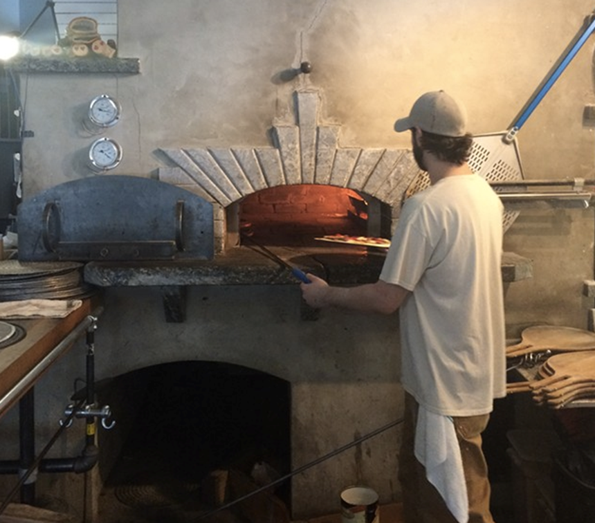 staff cooking a pizza in the shelburne oven